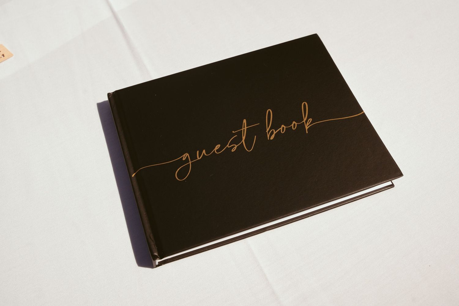 Black guest books with gold script lettering arranged in a minimalist style on white surface.