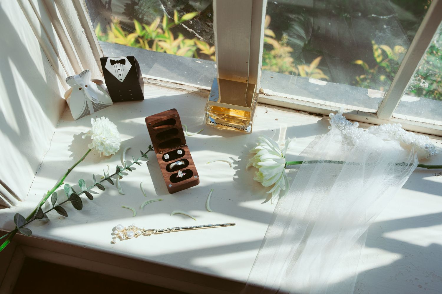 Wedding accessories and jewelry boxes arranged on a sunny windowsill.