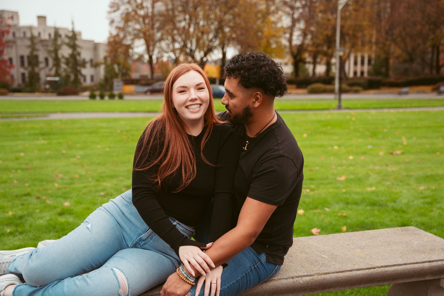 Romantic couple sharing intimate moments on a park bench surrounded by fall foliage.