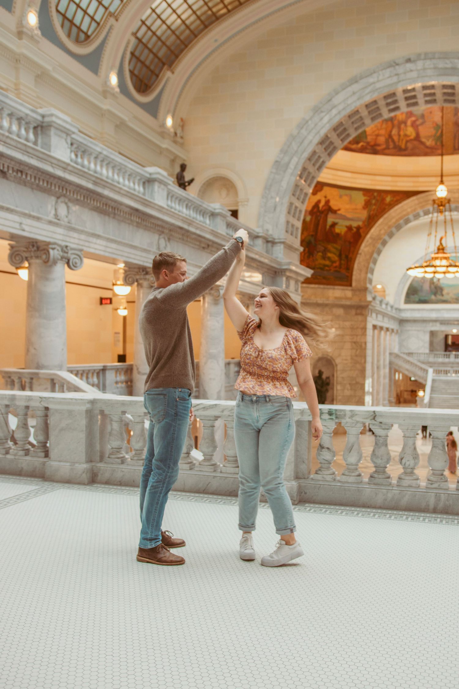 Couple dancing in a beautiful marble hallway with ornate architectural details.