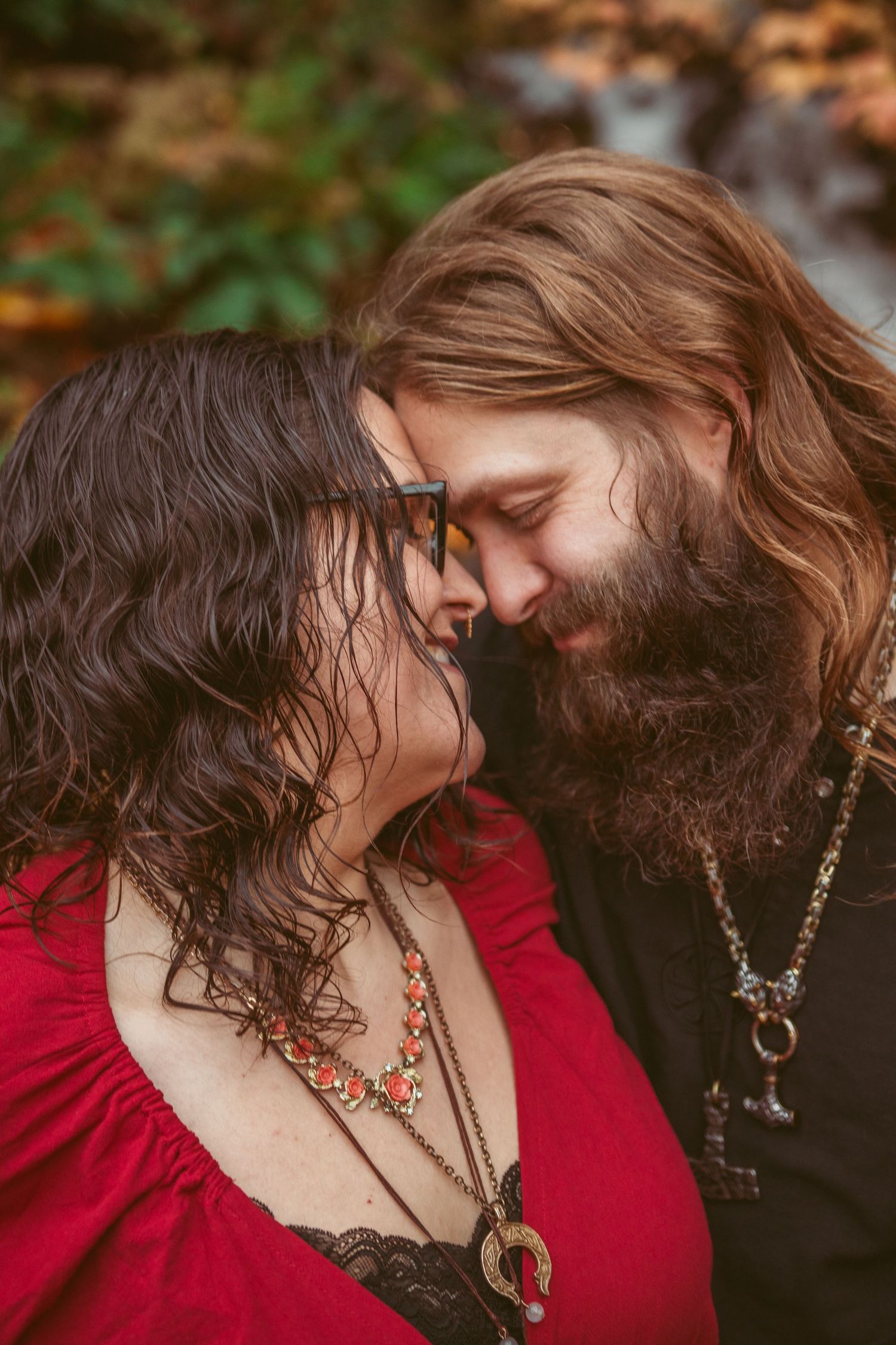 An intimate close-up moment between two people wearing red and black in an outdoor setting.