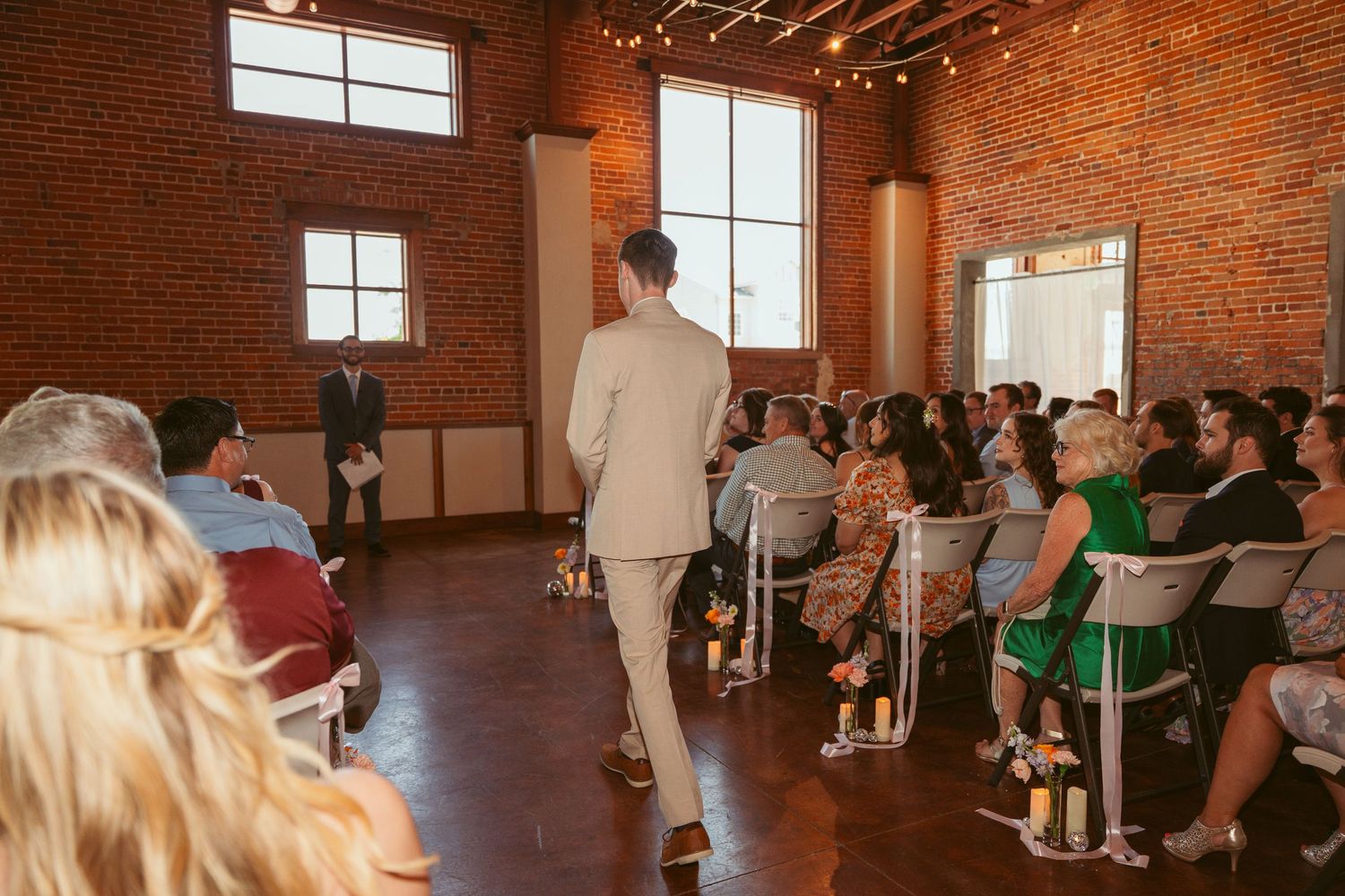 Wedding ceremony in a spacious industrial venue with exposed brick walls and natural lighting.