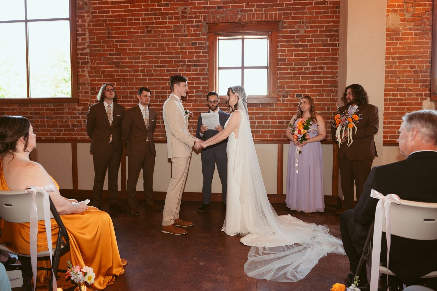 Wedding ceremony scene with attendees gathered in industrial-style brick venue.