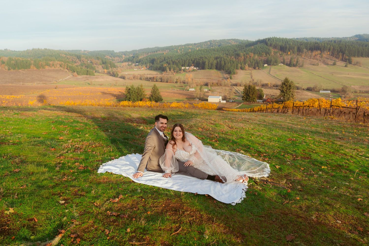 Wedding couple laying on a blanket with rolling hills and mountains in the background.
