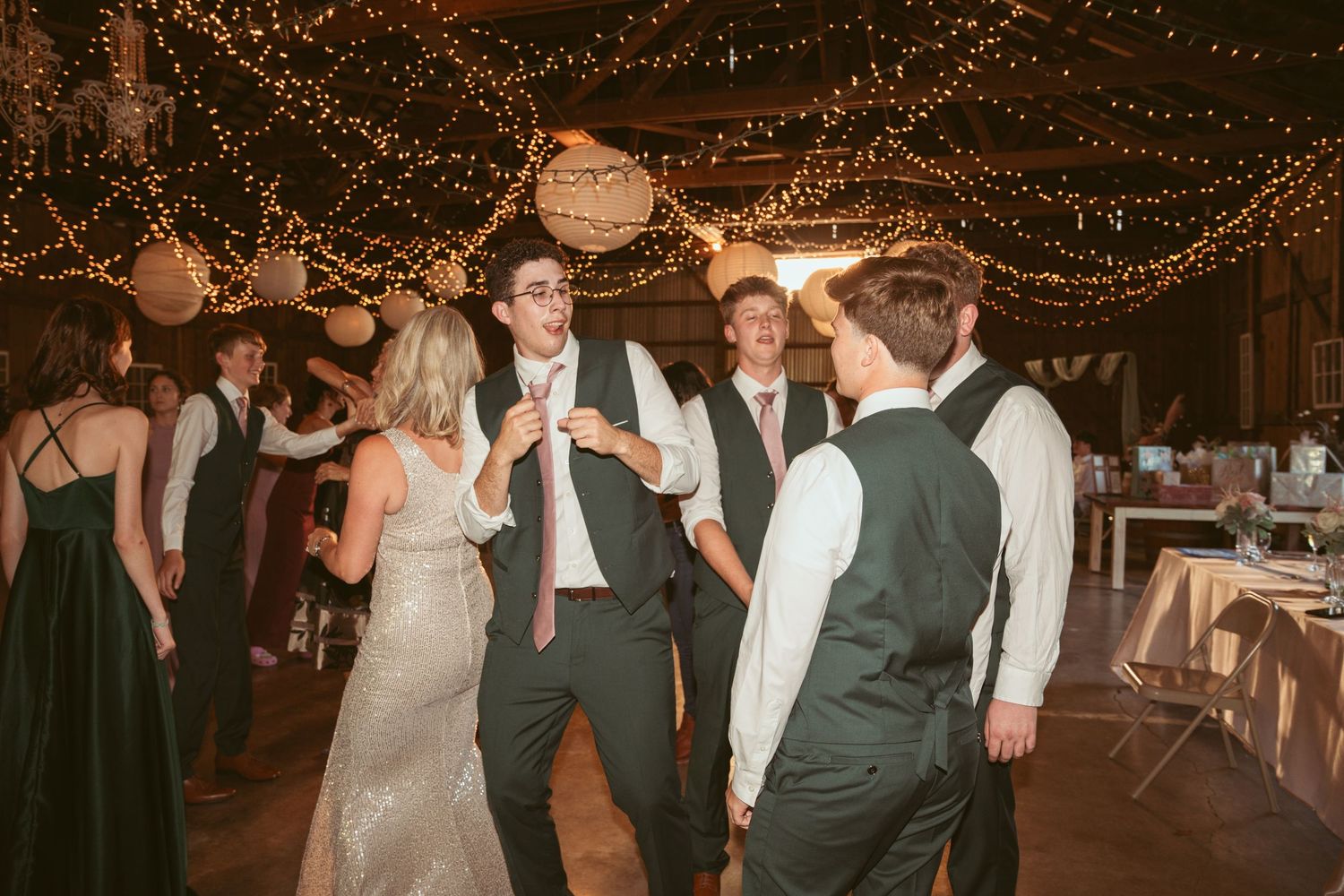 Group of guests dancing and socializing at a festive indoor wedding reception.