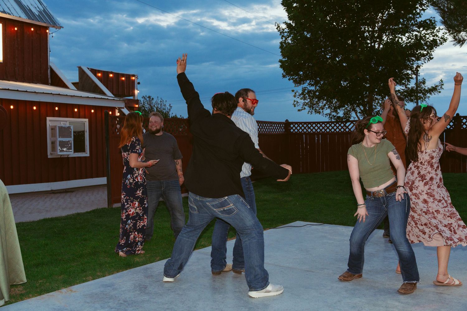 Group dancing and celebrating on an outdoor patio under blue skies.