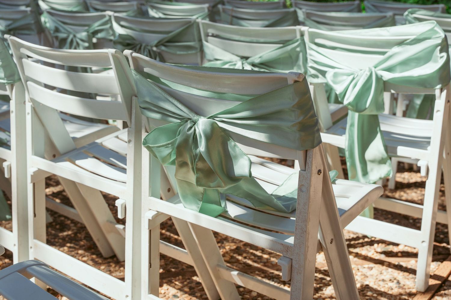 Row of white folding chairs set up for an outdoor event with soft lighting.