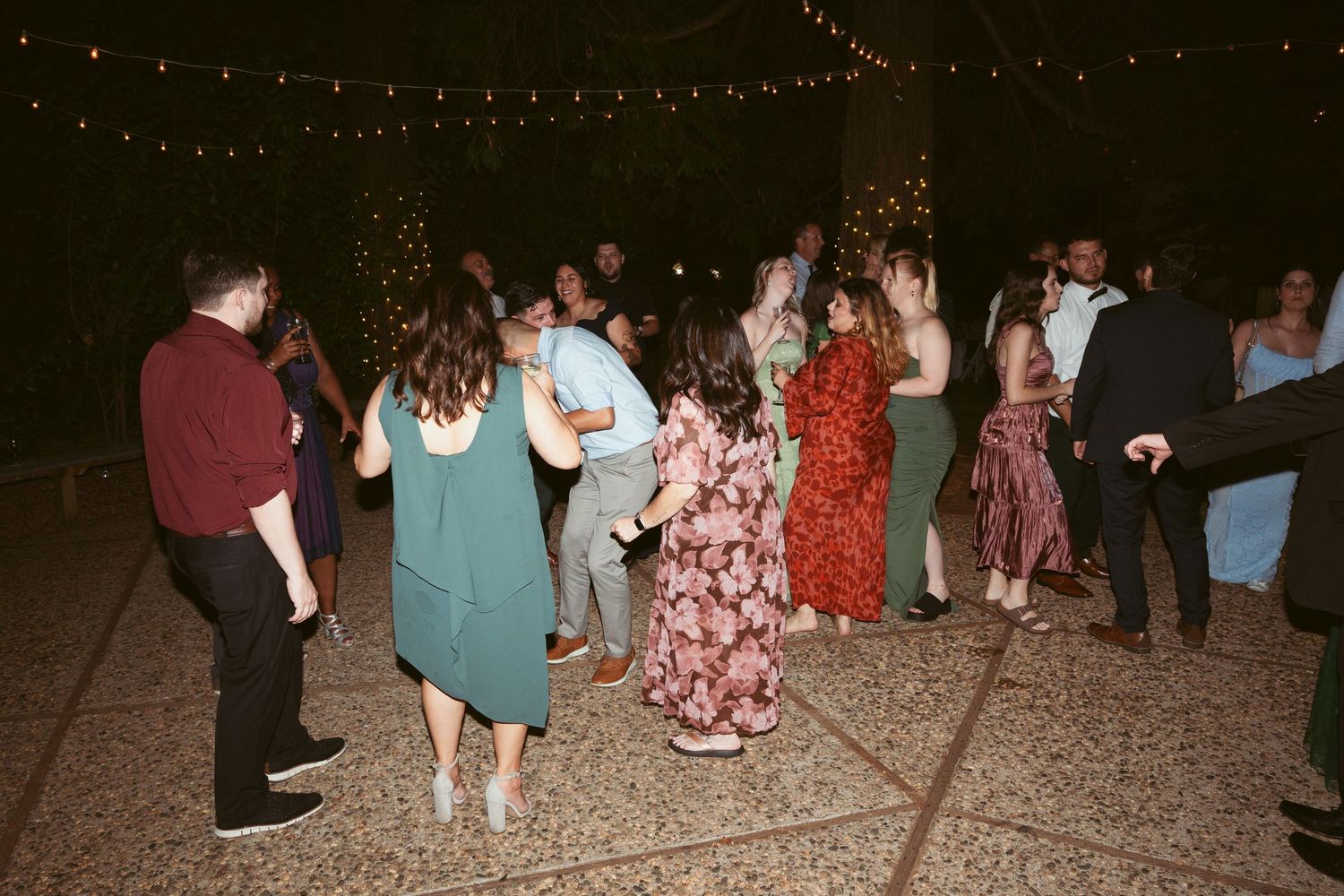 Nighttime wedding celebration with string lights and dancing guests.
