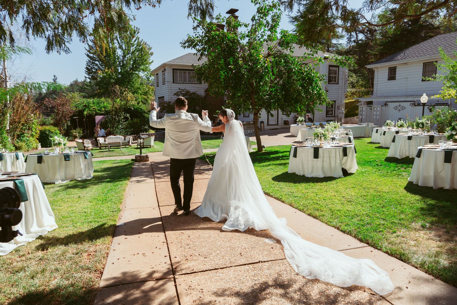 Wedding celebration in a sunny garden setting with white chairs and decorations.