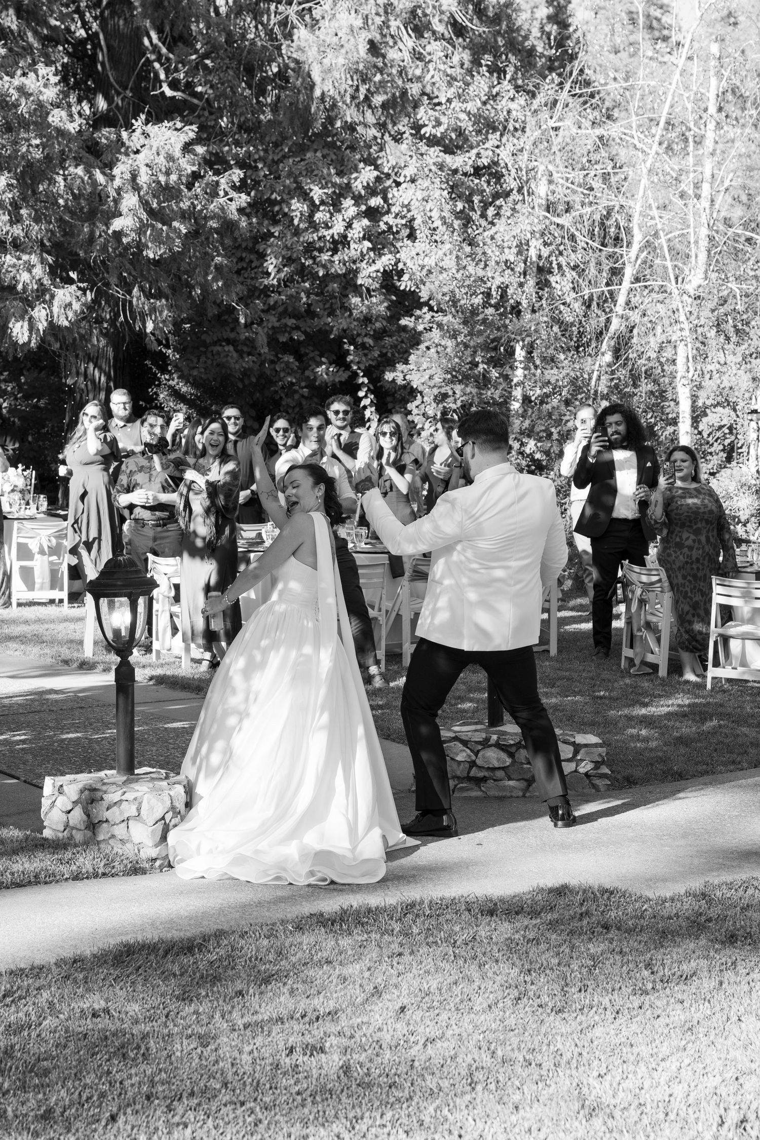 Black and white photo of wedding party walking across a grassy outdoor venue.