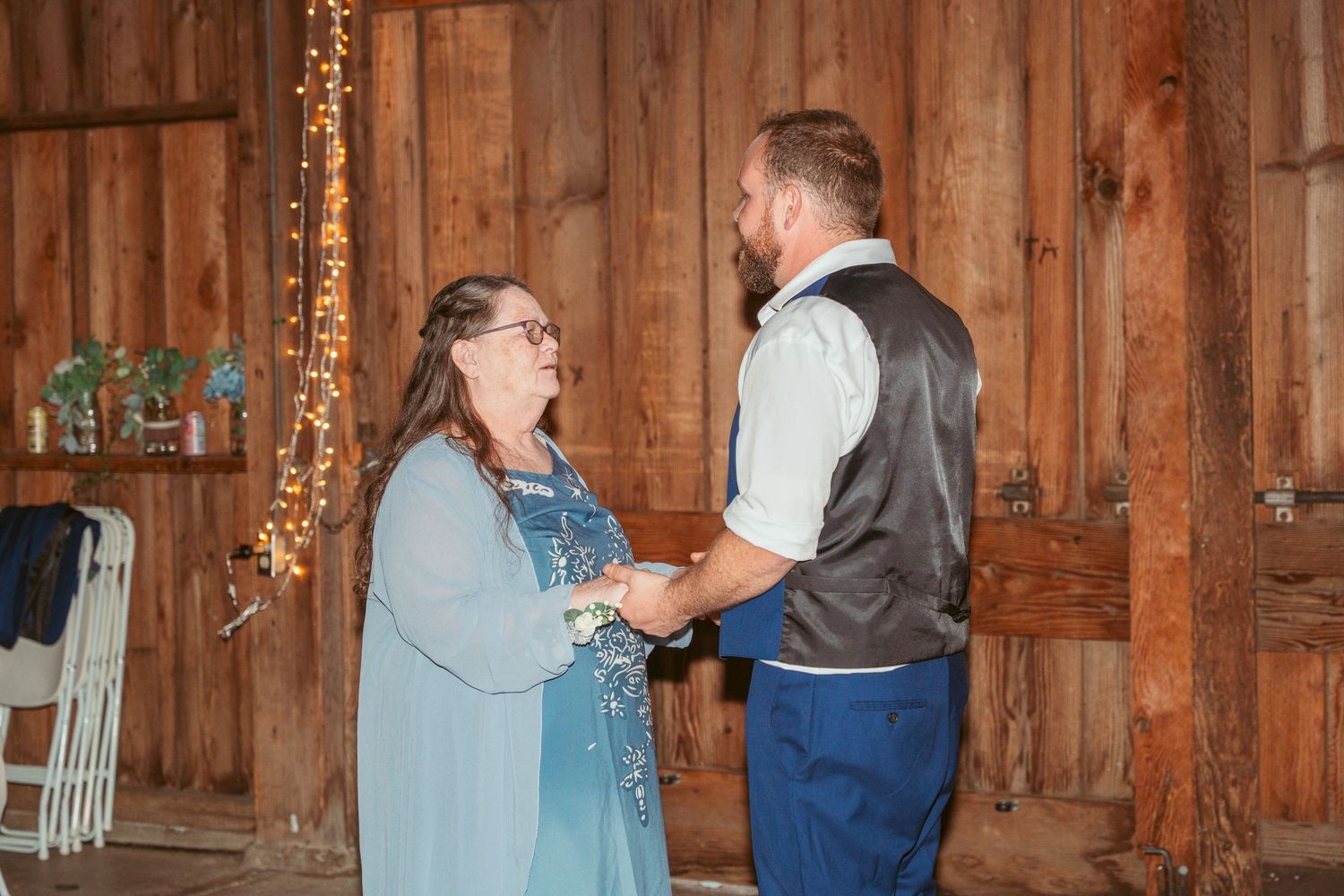 Couples share a dance moment in a warmly lit rustic barn setting.