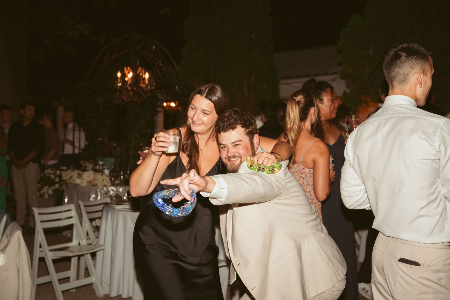 Wedding reception guests dancing and celebrating on an outdoor patio at night.