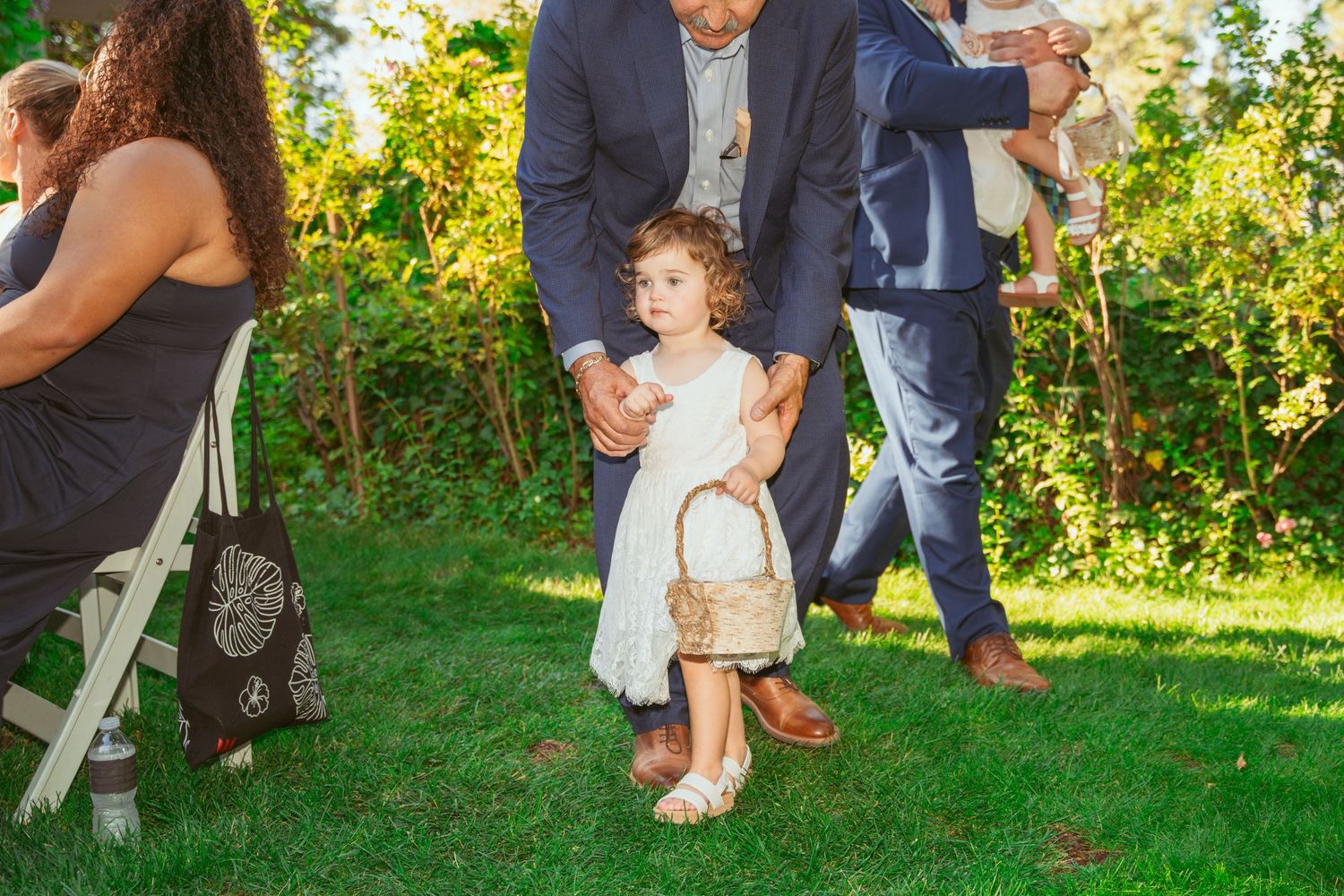 Wedding guests gather on a lush green lawn during an outdoor celebration.