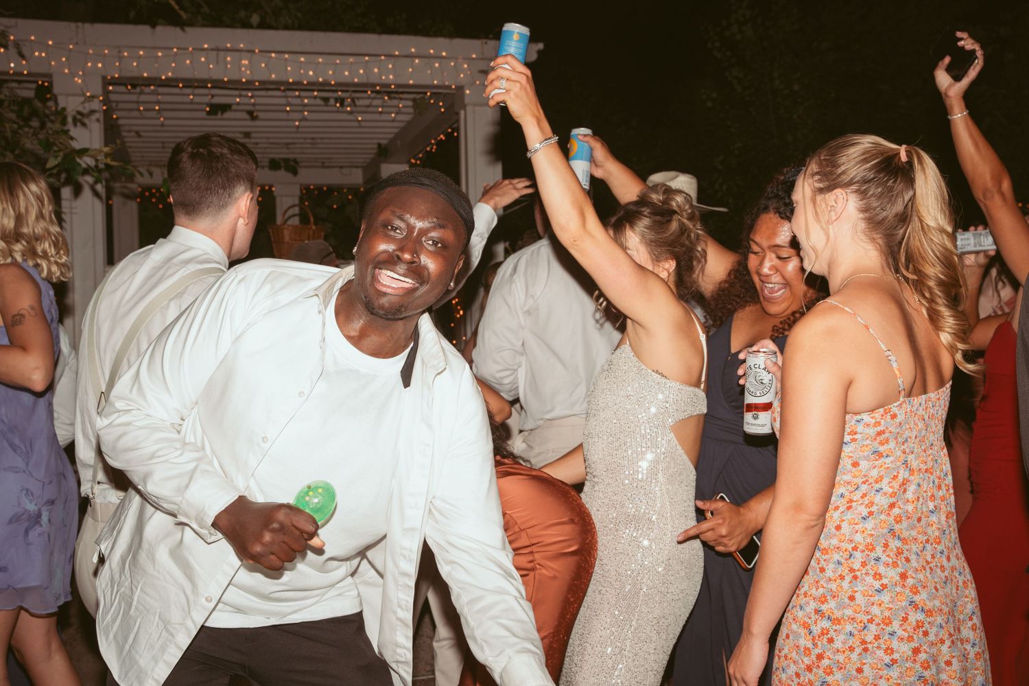 Wedding guests dancing and raising drinks during a lively reception party.