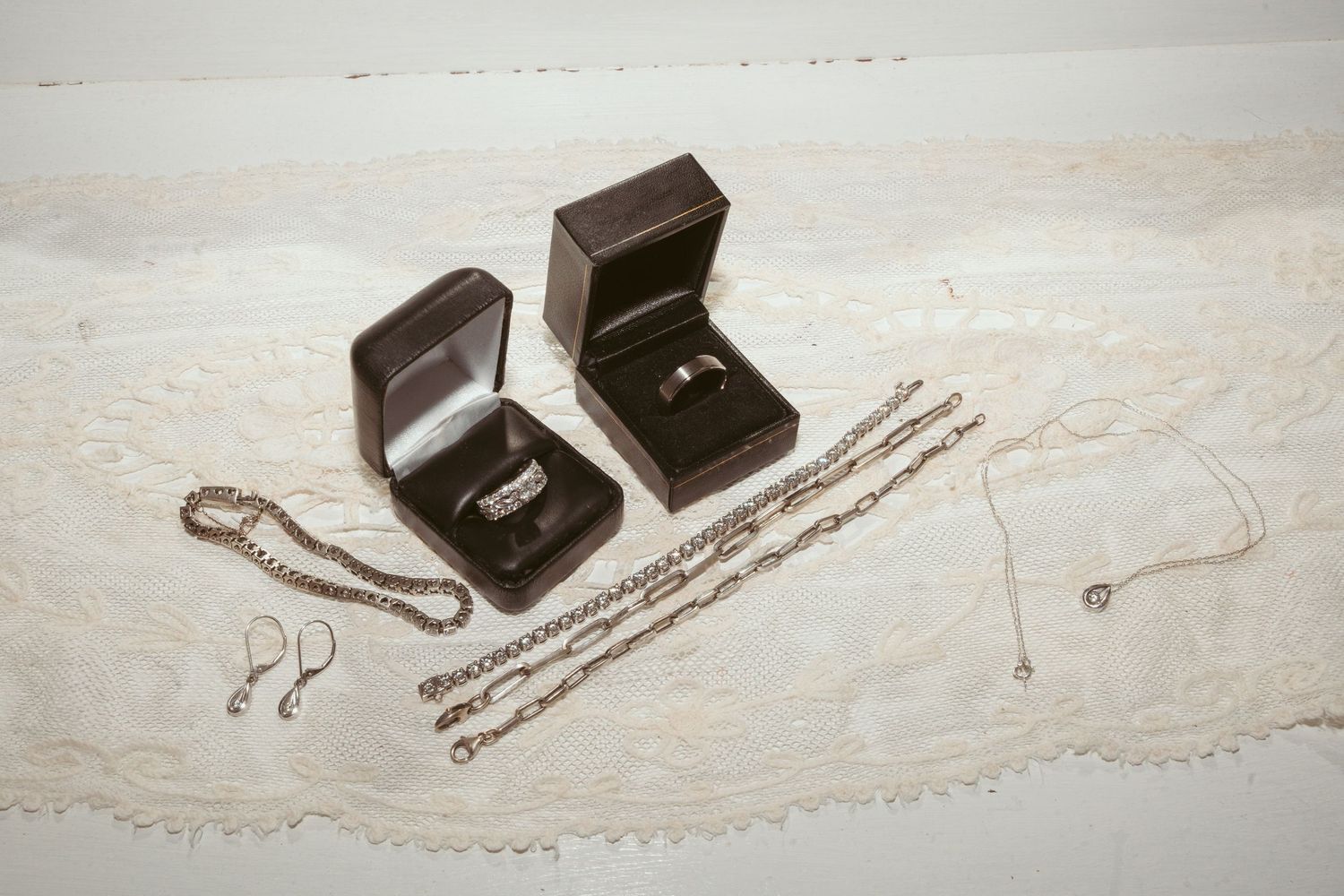 A sequence of jewelry boxes and necklaces arranged in a progressive reveal layout on a light surface.