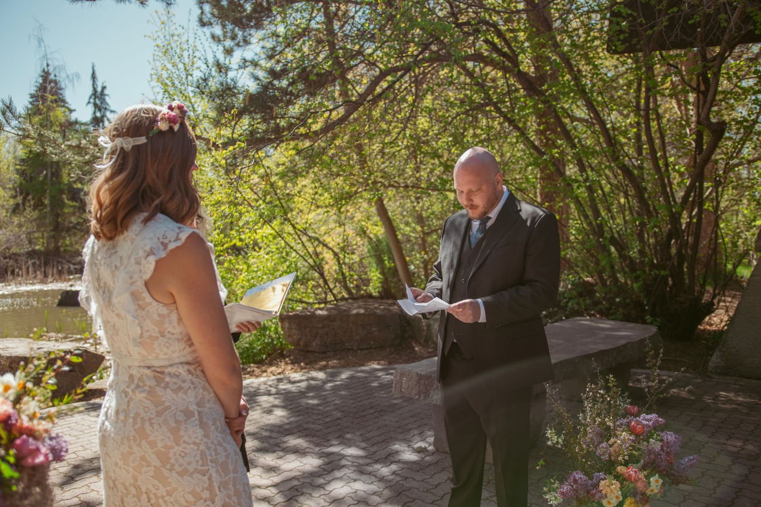 A wedding ceremony takes place outdoors on a sunny autumn day surrounded by trees and natural scenery.