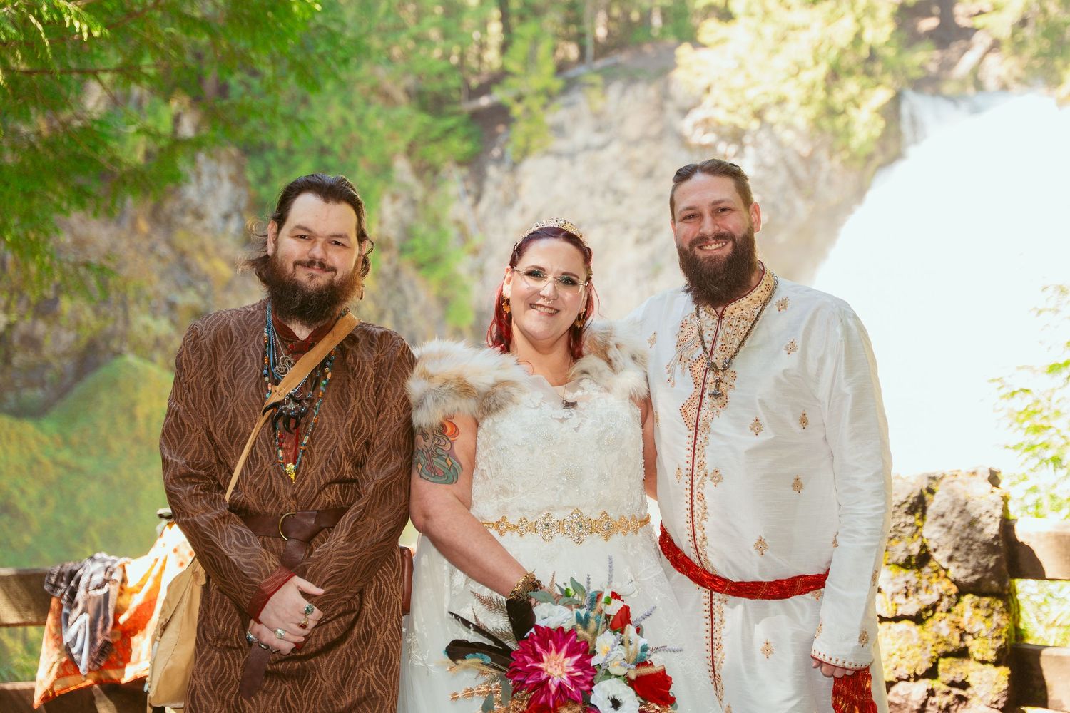 A wedding celebration group wearing renaissance-style clothing poses together in a forest setting.