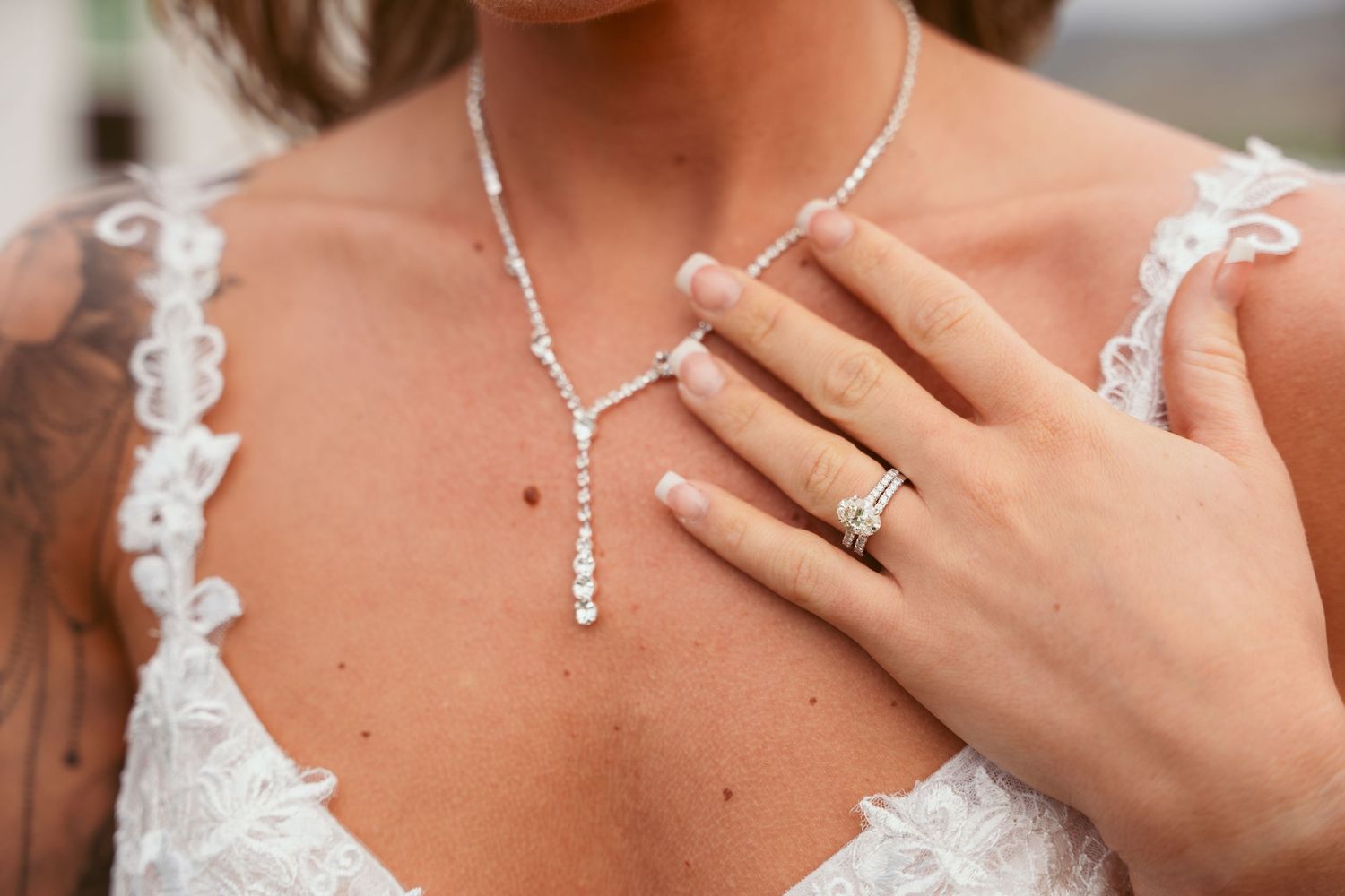 Detail shot of a Y-shaped crystal necklace and lace wedding dress neckline.