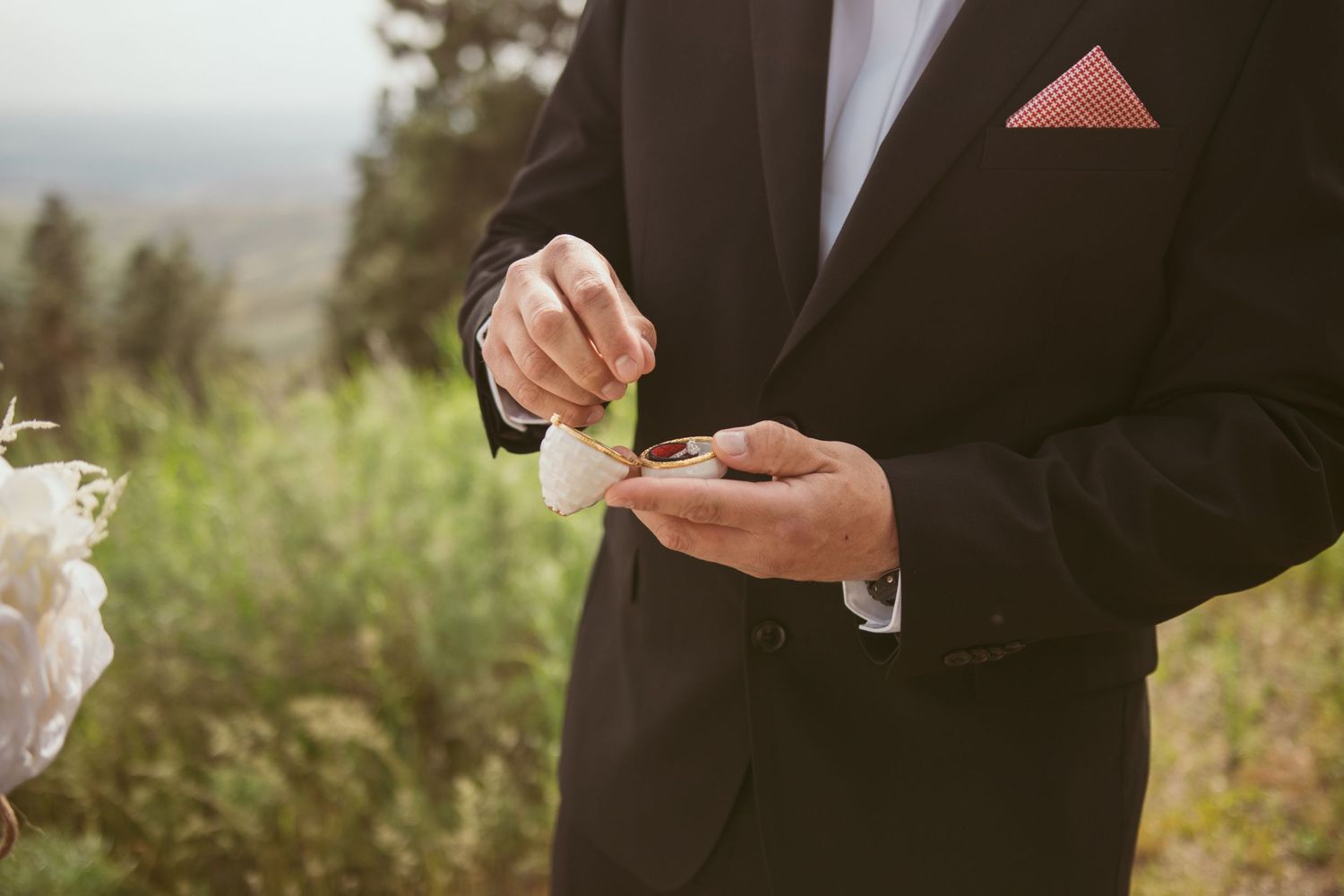 Wedding ceremony details with formal attire against a natural outdoor backdrop.