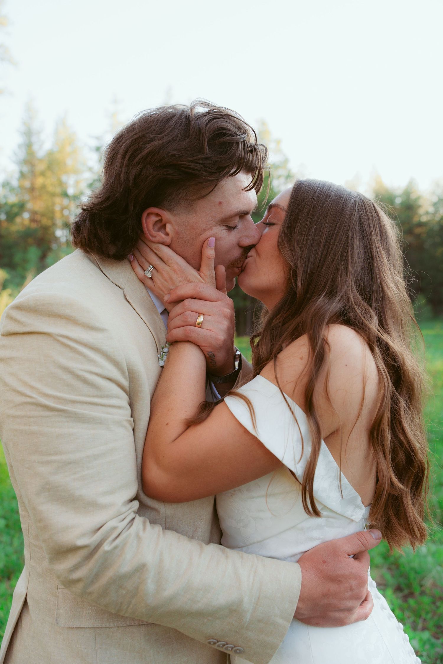 Romantic wedding couple sharing tender moments in a sunlit meadow.