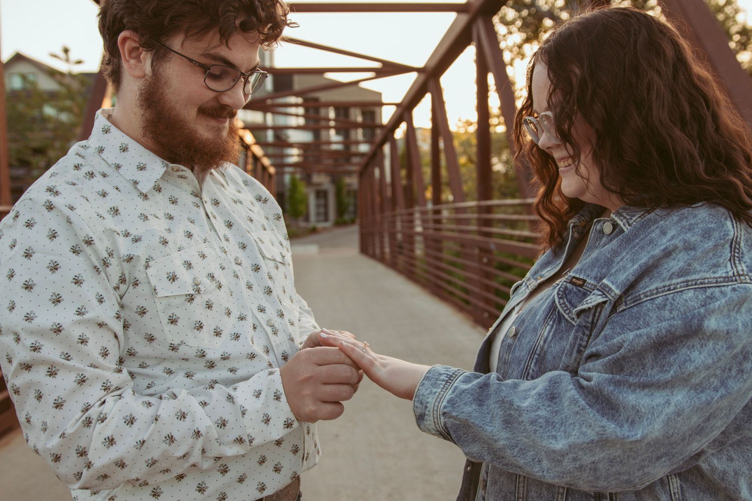 A couple shares playful moments on a bridge during sunset.