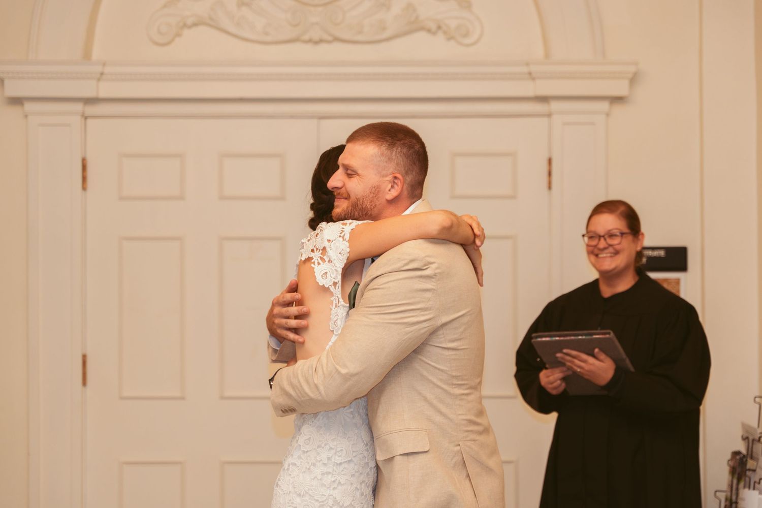 A couple embraces in an elegant indoor setting during their first look wedding moment.