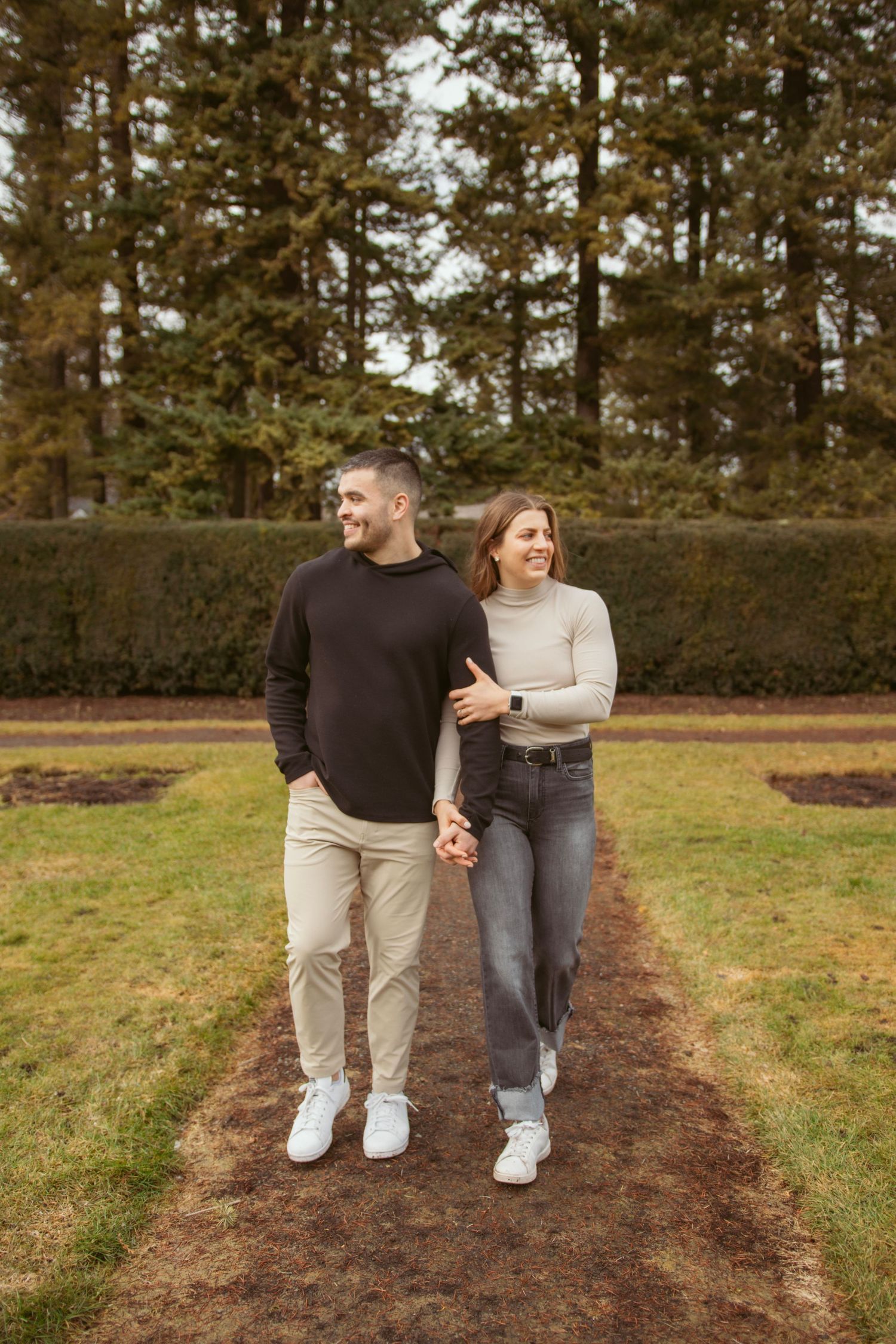 A couple walking together on a dirt path through an autumn landscape.