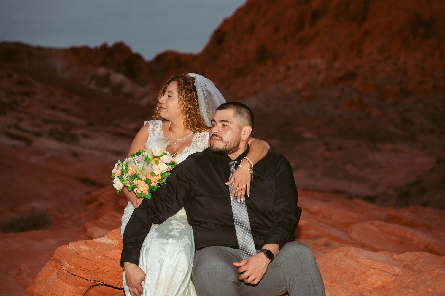 A romantic wedding photo session against stunning red rock formations in the desert at sunset.