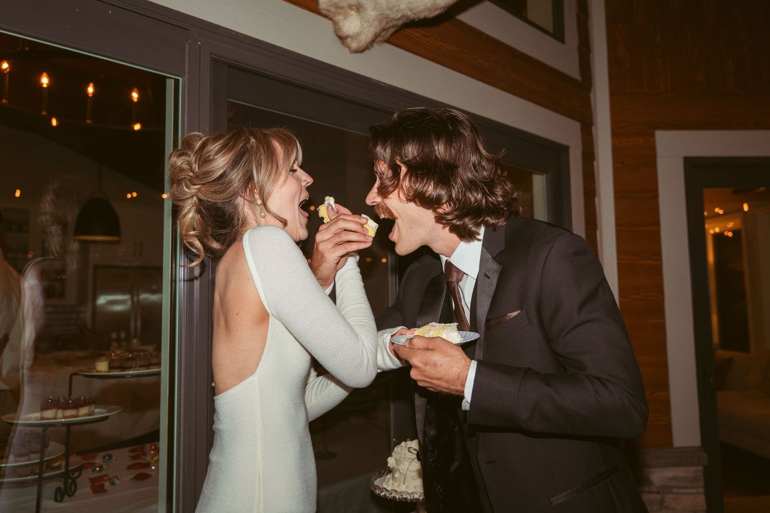 A couple shares a fun moment with wedding cake at their indoor reception.