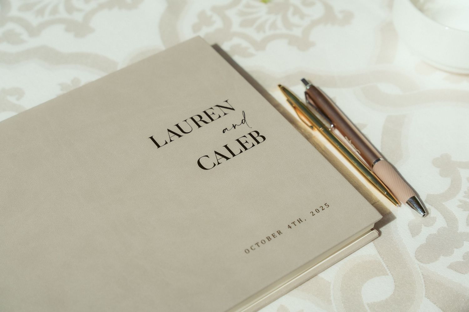 Elegant wedding invitation book displayed on white textured fabric.