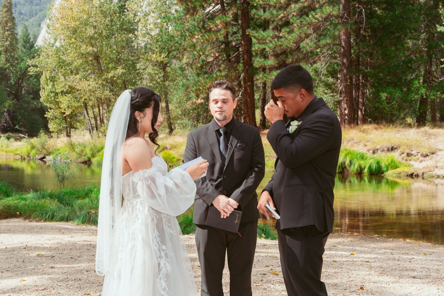 Outdoor wedding ceremony with lake and pine trees in the background.
