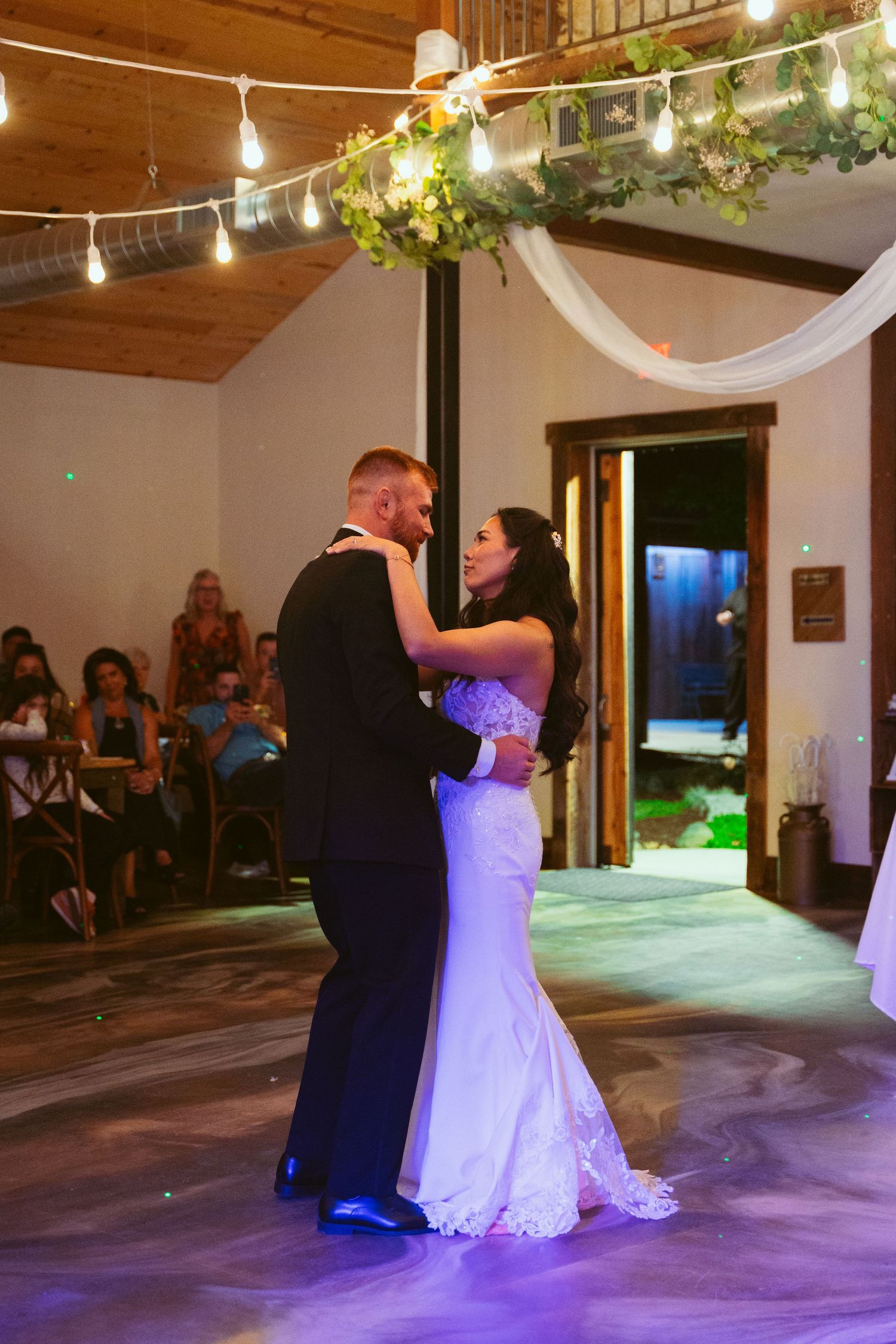 Wedding couple performing their choreographed first dance under romantic string lights.