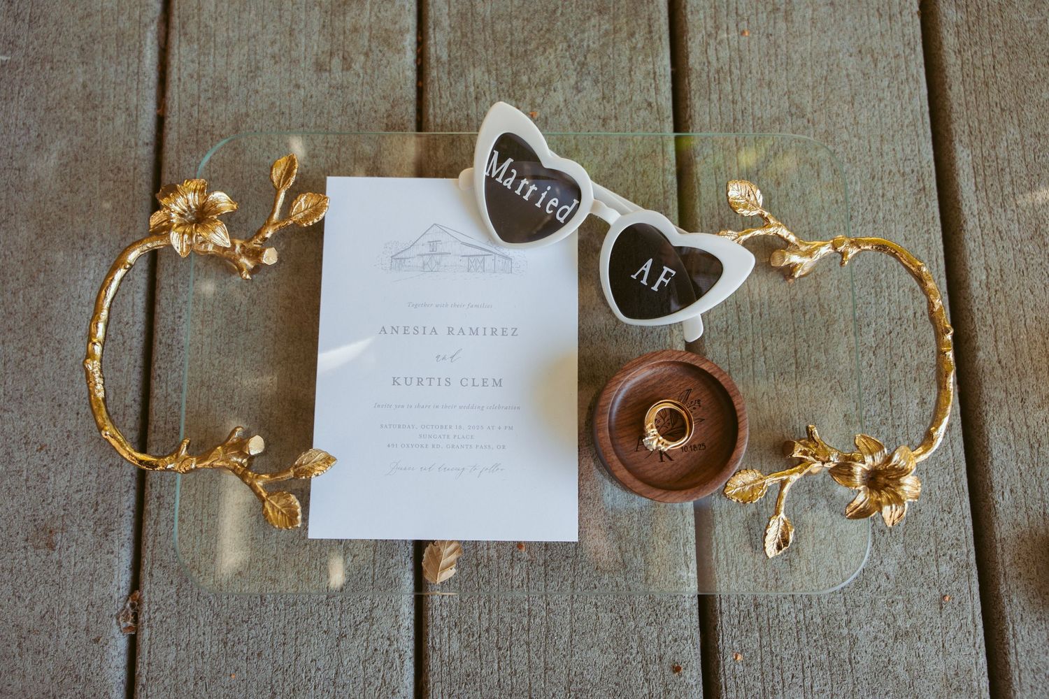 Wedding details including rings and decorative elements arranged on weathered wood surface.