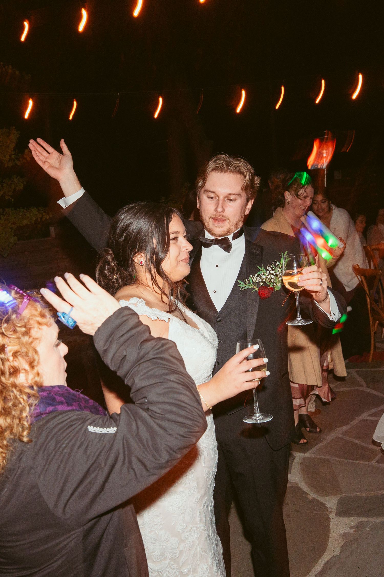 Wedding celebration with dancing couples and colorful party lights illuminating the dance floor.