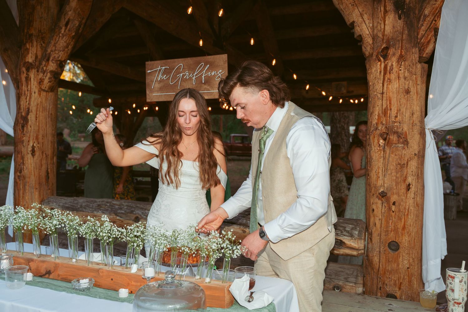 Wedding celebration in a rustic wooden barn venue decorated with twinkling lights and white draping.