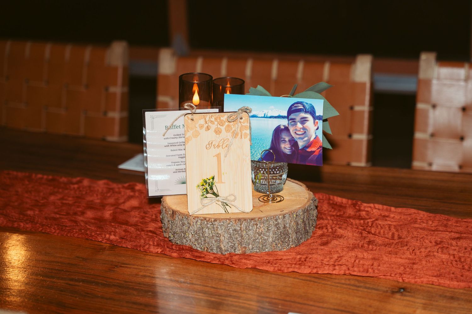 Table centerpiece with candles and decorations on red runner.