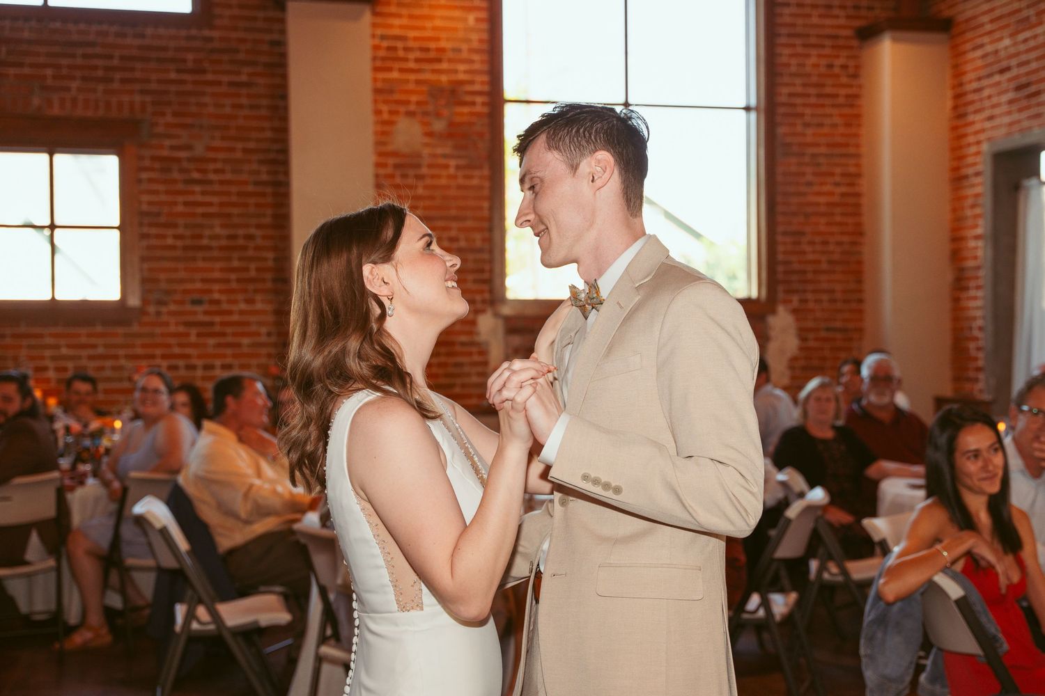 Couple shares an intimate moment during their wedding reception in a brick-walled venue.