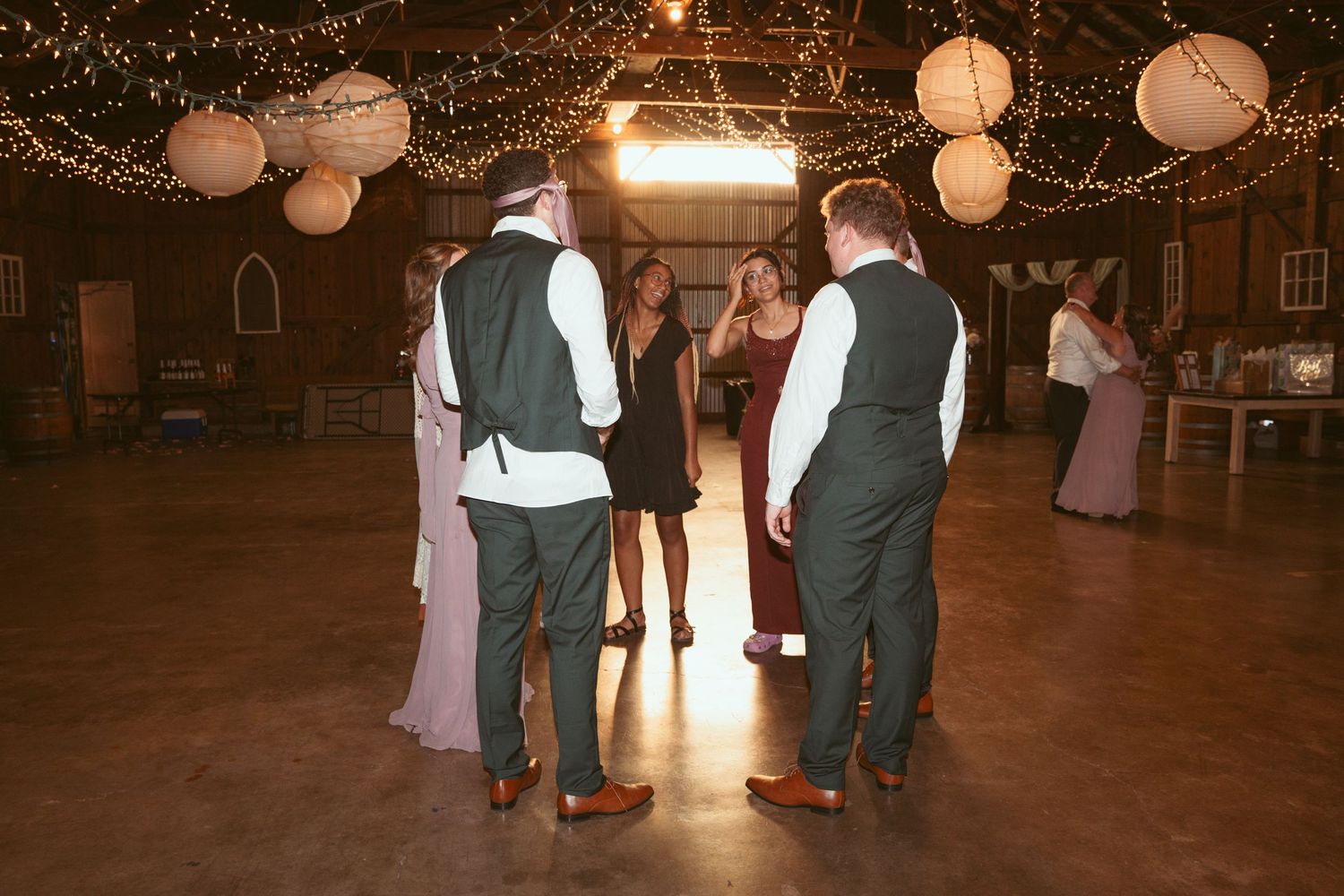 Wedding reception dance floor with guests celebrating under glowing lights and lanterns.