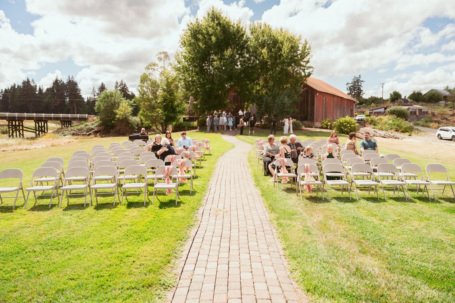 Panoramic view of an outdoor wedding ceremony setup with white chairs on a grassy field.