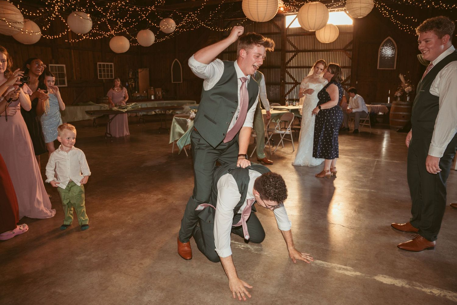 Guests dancing and having fun under decorative lights at an indoor wedding venue.