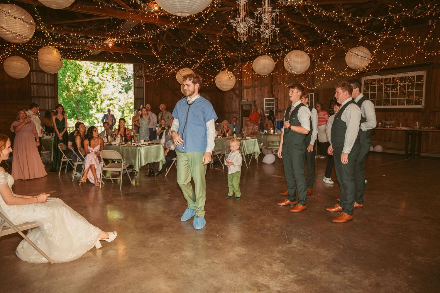 Guests enjoying a lively dance party under warm lighting in a rustic barn wedding venue.
