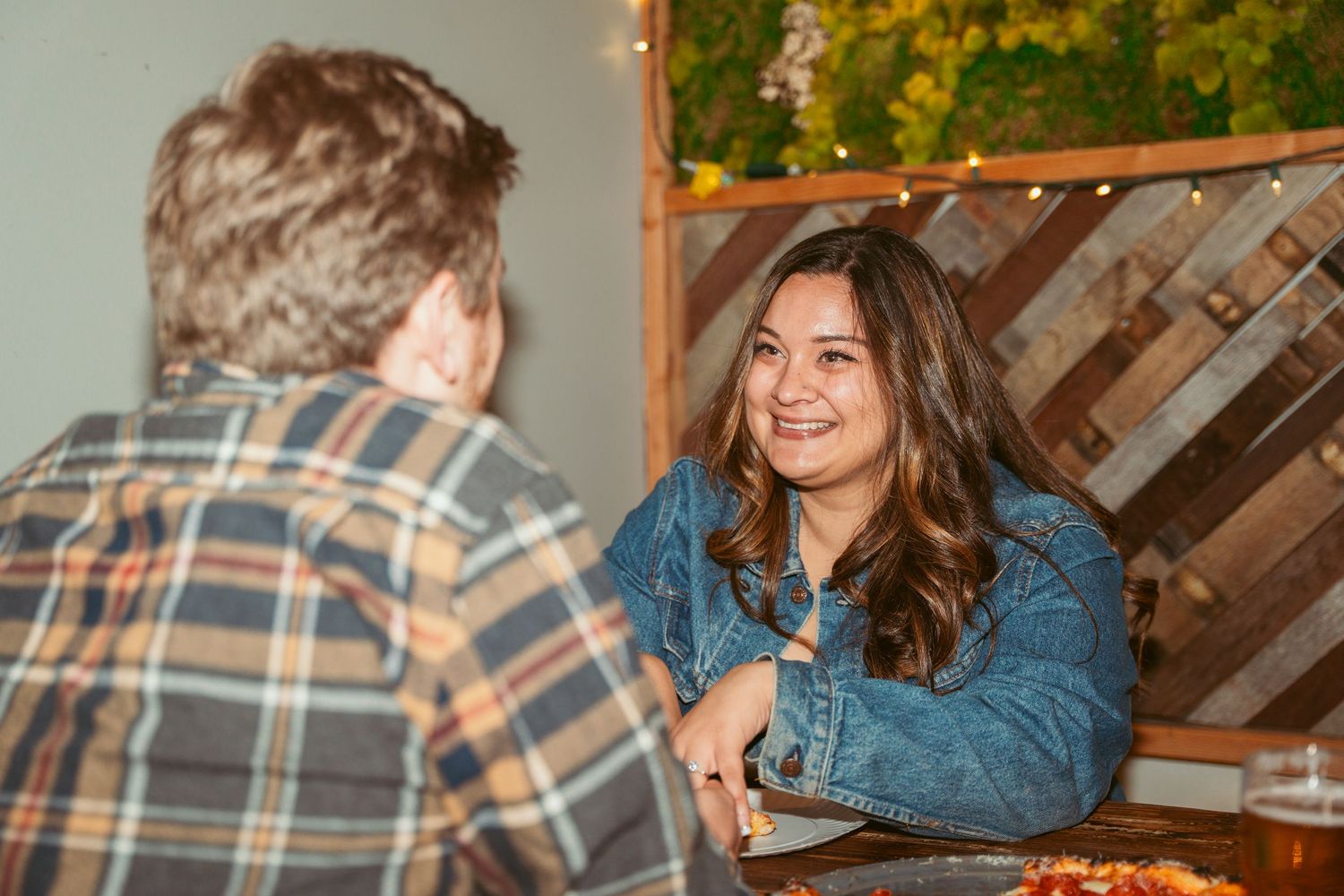 Friends laughing while sharing a meal at a restaurant with wood paneled walls.