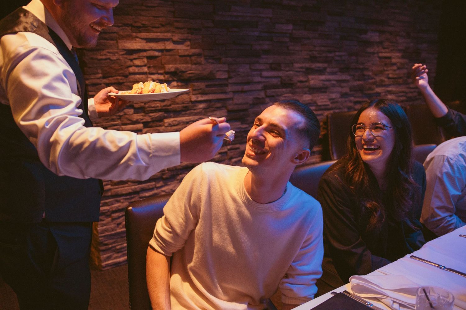 Wedding reception guests enjoying themselves in a dimly lit venue with stone walls.