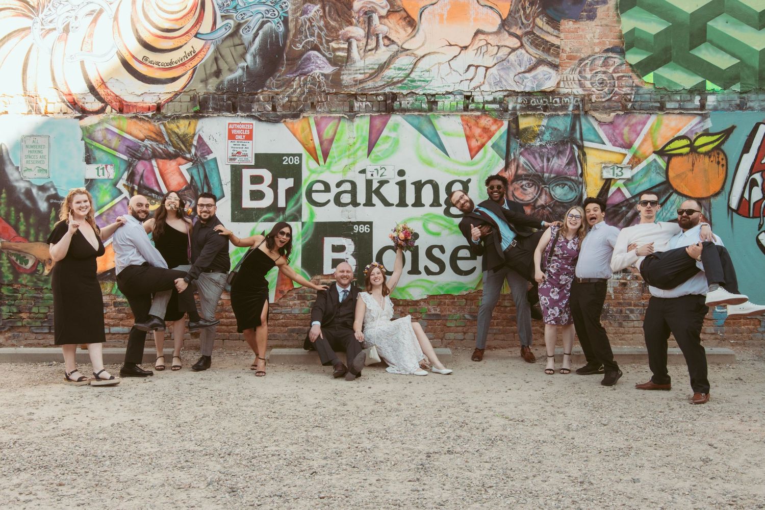 Group of people dancing in front of vibrant street art and graffiti murals during a celebration.