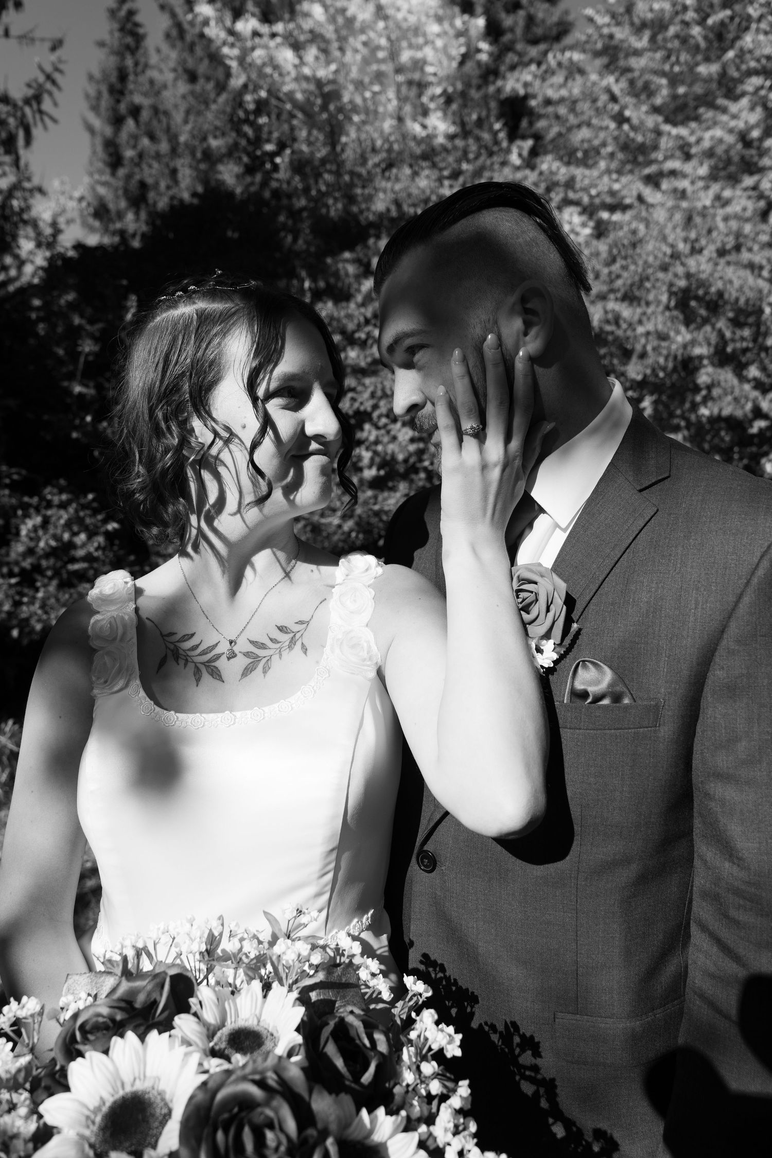 Black and white portrait of couple sharing intimate moment with sunflower bouquet.