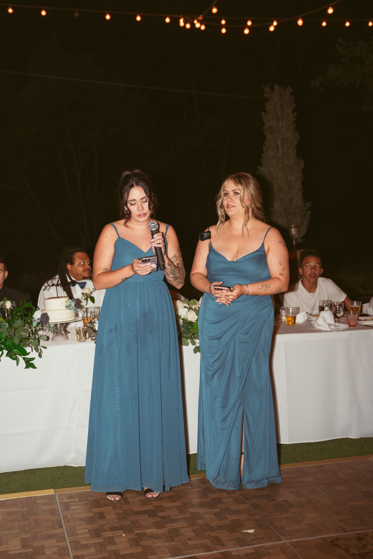 Bridesmaids in matching blue dresses standing together at an evening wedding reception.