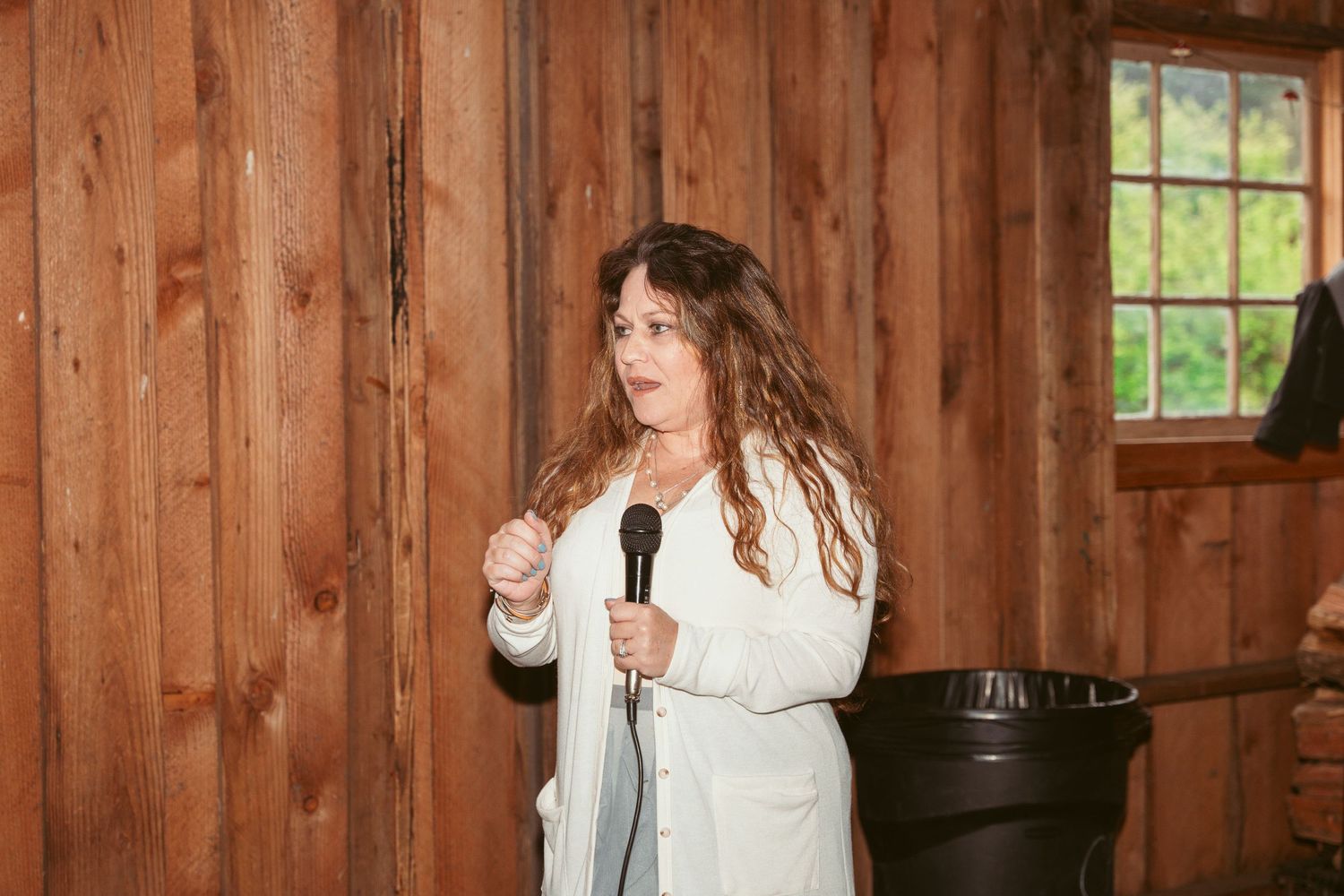 Wedding party giving toasts at head table in rustic barn setting.