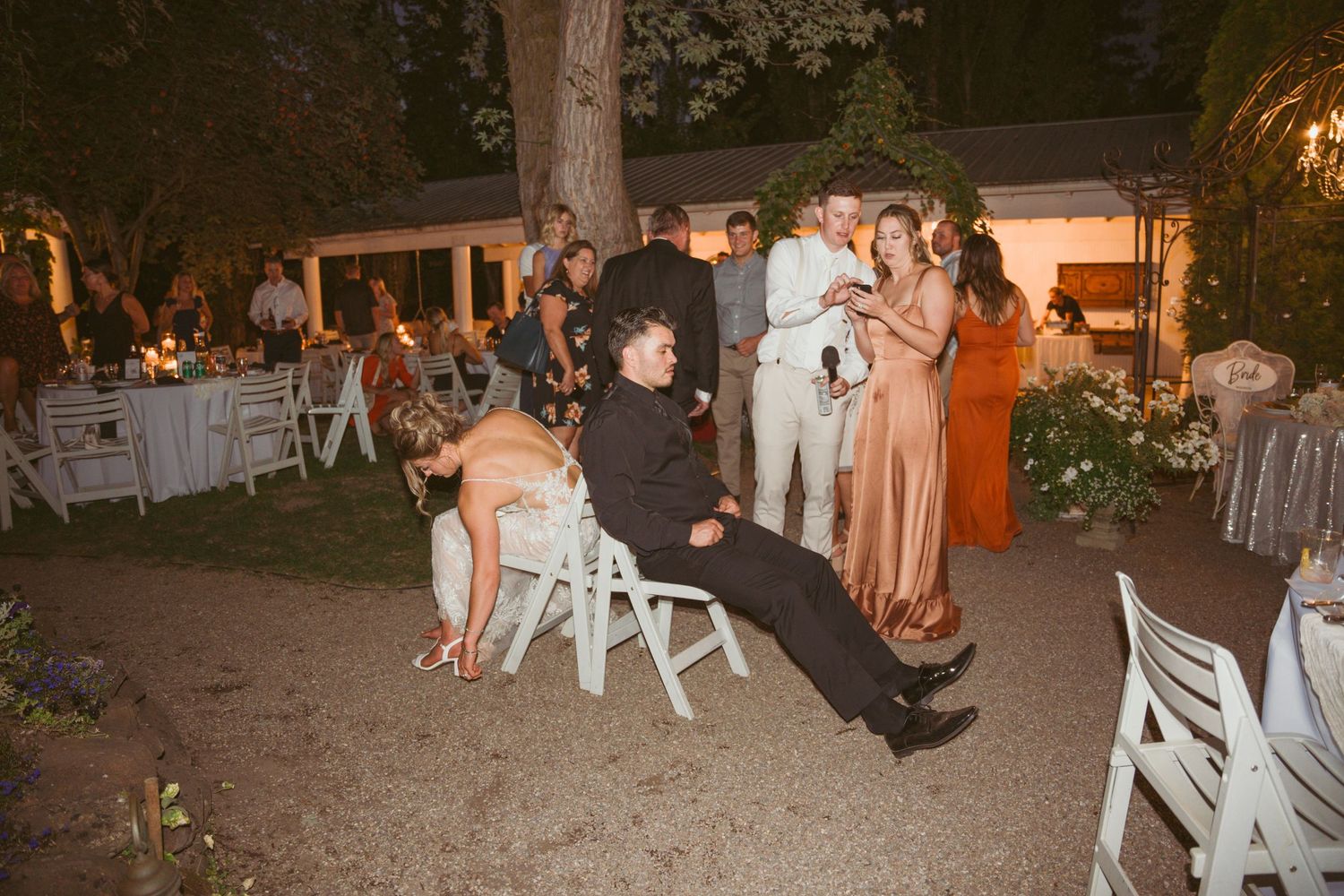 Evening wedding celebration showing guests socializing on a patio with ambient lighting.