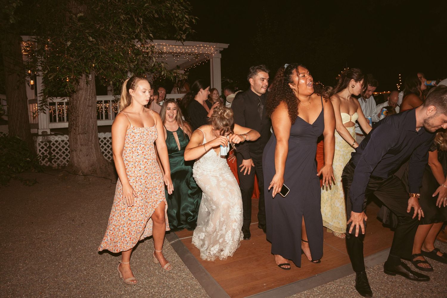 Wedding guests dancing together on an outdoor dance floor during evening celebration.