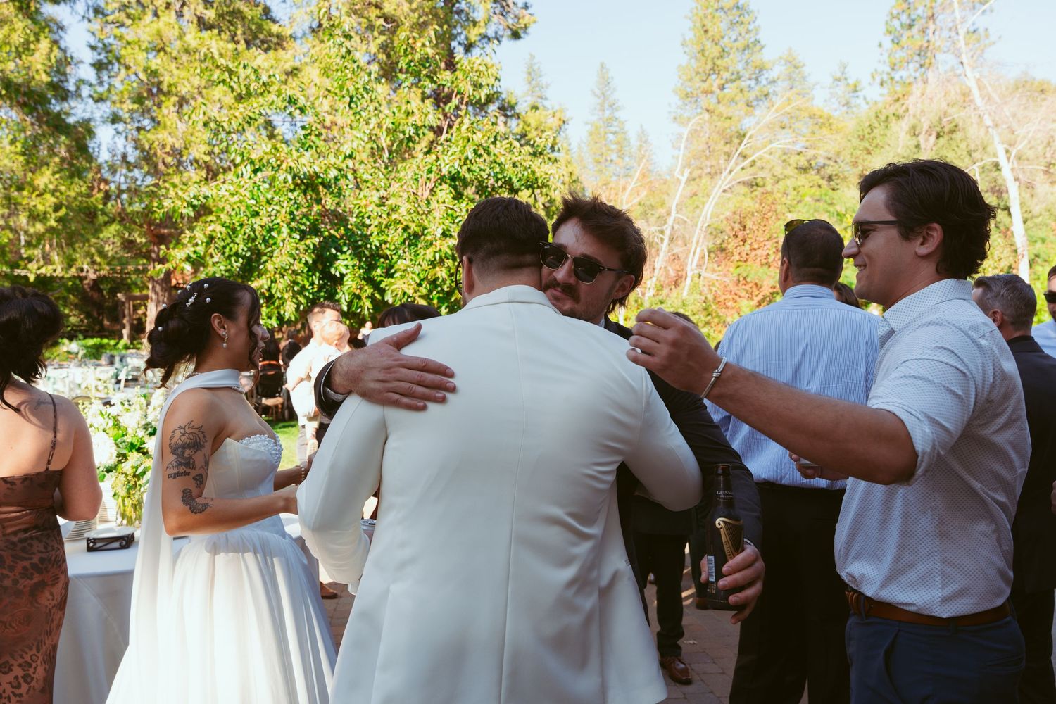Wedding party members dance together during an outdoor afternoon celebration.